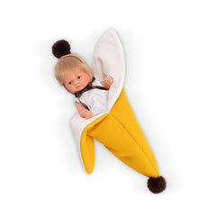 Small baby doll wrapped in a banana-themed yellow and white cloth, with brown pom-pom accents.