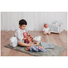 Child playing with doll and Asi Dolls bathroom accessories on a soft rug; includes quilted baskets and plush toys.