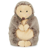 Piksi the Hedgehog, a soft stuffed animal with a cream belly and gray, fuzzy exterior, holds its paws together. It features a cute face with black eyes and a small brown nose, topped with a simple striped collar, inviting cuddles and imaginative play.
