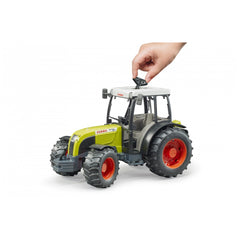 Hand adjusting the roof of a green and white Bruder Claas Nectis 267 F toy tractor with red wheels.