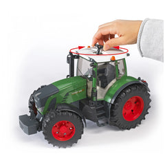 Hand rotating the steering wheel on a green Bruder Fendt 936 Vario toy tractor with red wheels.