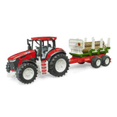 Red toy tractor with white wheels and a green trailer carrying three tree trunks. Suitable for forestry play.
