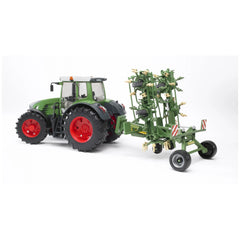 Green toy tractor with red wheels towing a green rotary tedder attachment, showcasing agricultural play realism.