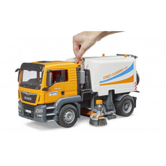 Hand interacting with Bruder MAN TGS Street Sweeper toy, showcasing detailed orange and white design with movable parts.