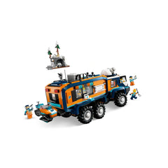 LEGO Arctic Explorer Science Lab Truck in orange and blue, featuring six wheels, equipped with tools and laboratory. Mini-figures explore the snowy terrain with trees and a cave in the background.