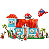 Lego Disney Lilo and Stitch Beach House construction set features a vibrant two-level beach house with red-tiled roof, surrounded by palm trees. Lilo and Stitch figures, surfboards, and playful details like a guitar and Scrump doll enrich the scene.