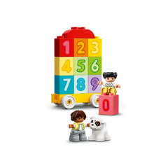 Colorful LEGO® DUPLO® Number Train with stacked number blocks. Two children figures play beside a white dog, engaging in imaginative learning.