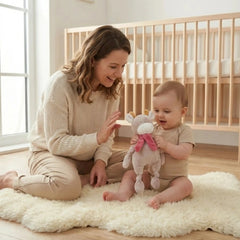 Artesavi Cow Plush Rattle 32 Cm held by a smiling child in a cozy nursery with soft lighting and neutral decor.