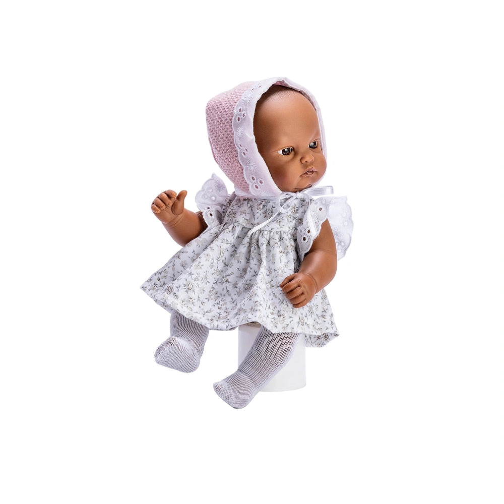 Gordi doll in a flower dress with pink hood, seated, showing articulated limbs and light eyes against a white background.