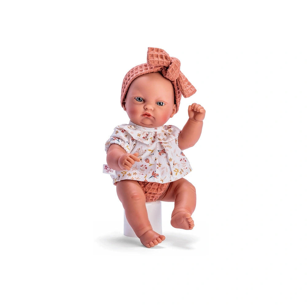 Gordi doll in floral shirt, pink headband, and panties, sitting with one arm raised, showcasing expressive face and light eyes.