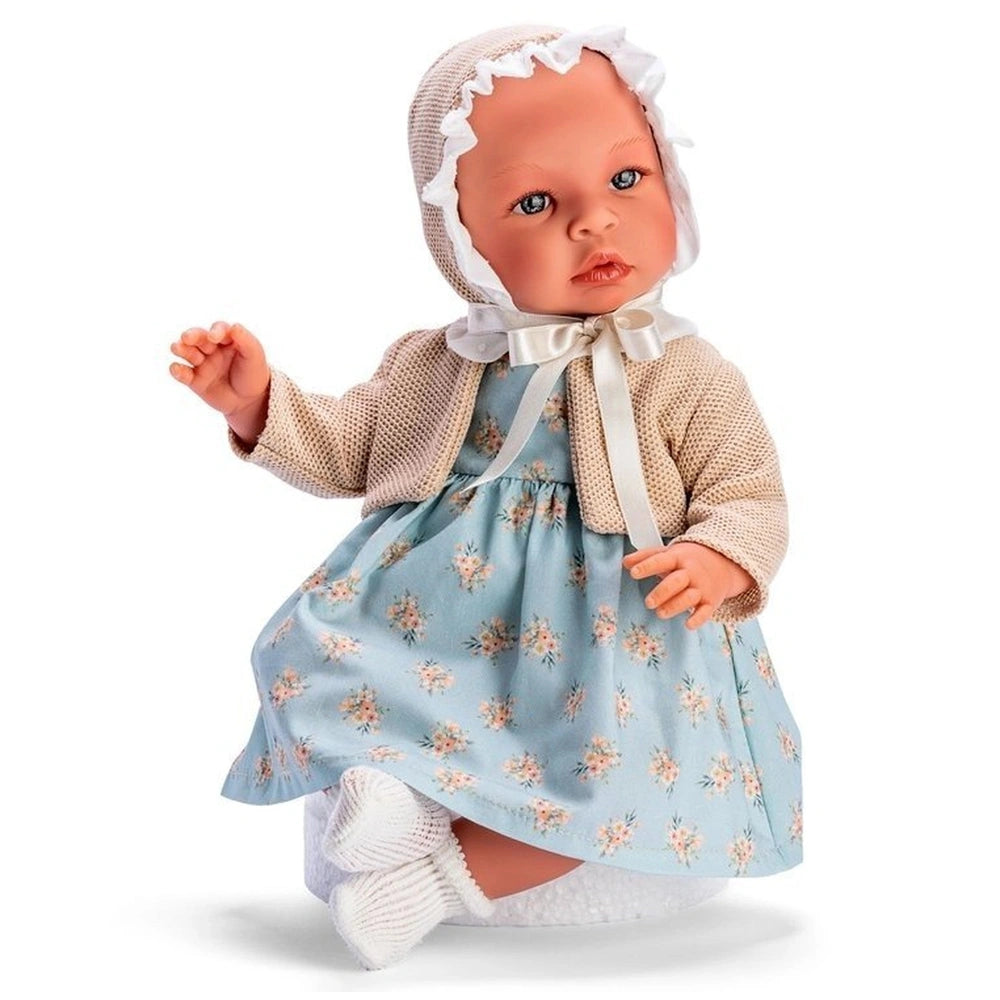 Asi Doll Leo in blue dress with orange flowers, beige jacket, and white bonnet sitting, showcasing a realistic design.