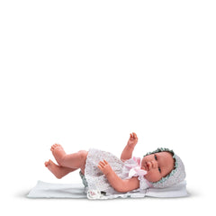 Asi Doll María in a floral Cloe Collection dress and bonnet, lying on a white blanket.