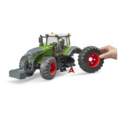 Hand demonstrating removable wheel on green Bruder Fendt 1050 Vario toy tractor with red rims.