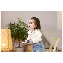 Eichhorn Baby Wooden Rattle Rabbit is held by a toddler in a cozy indoor setting with a potted plant in the background.