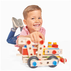 Eichhorn Constructor 4 in 1 construction set features a smiling child playing with a colorful wooden toy train on the floor.