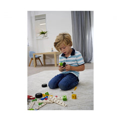 Eichhorn construction set toys are scattered around a child in a blue striped shirt, engaged in play on a white carpeted floo