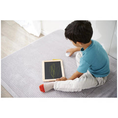 Eichhorn Small Blackboard with a child using a tablet, drawing in green, on a gray carpet in a minimal indoor setting.