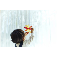 Folia transparent paper block with colorful sheets showcased by a child holding a red and yellow paper flower against a white