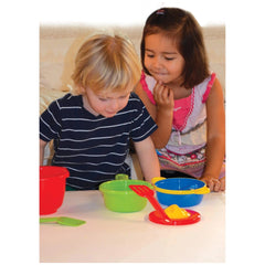 Gowi Cooking Set Vienna features 14 plastic pieces arranged on a wooden table with children engaging in pretend play.