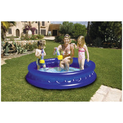 Blue inflatable pool in a green yard with three people: a woman in a bikini, a child in a pink swimsuit, and a boy in blue tr