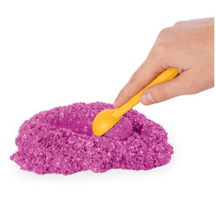 Kinetic Sand Shimmer Sparkle Sandcastle Set featuring a yellow plastic spoon resting on purple powdery sand.