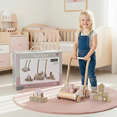 a pink and white wooden educational baby walker with various vehicle designs, as a young girl in blue overalls holds it.