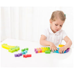New Classic Toys Alphabet Puzzle features a blonde child in a white shirt, engaging with the crocodile puzzle on a white tabl