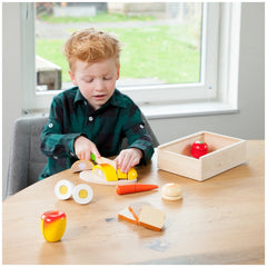 New Classic Toys breakfast box set with wooden and plastic toy food items displayed on a wooden table with a child playing.