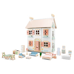 New Classic Toys wooden dollhouse features furniture, transparent plastic windows, and a cardboard roof and door.