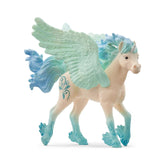 A glossy white unicorn foal figurine with blue accents on its mane, tail, and hooves stands on a white surface.