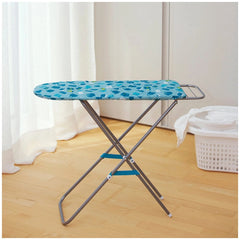 Theo Klein metal ironing board with blue patterned fabric, set against a white wall and light wood floor, beside a white laun