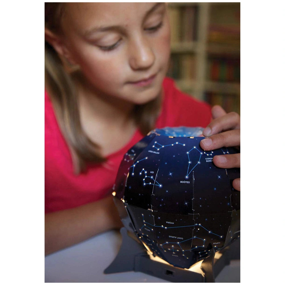 KidzLabs Night Sky Projection Kit with a girl in a red top touching a starry spherical object, eyes closed in wonder.