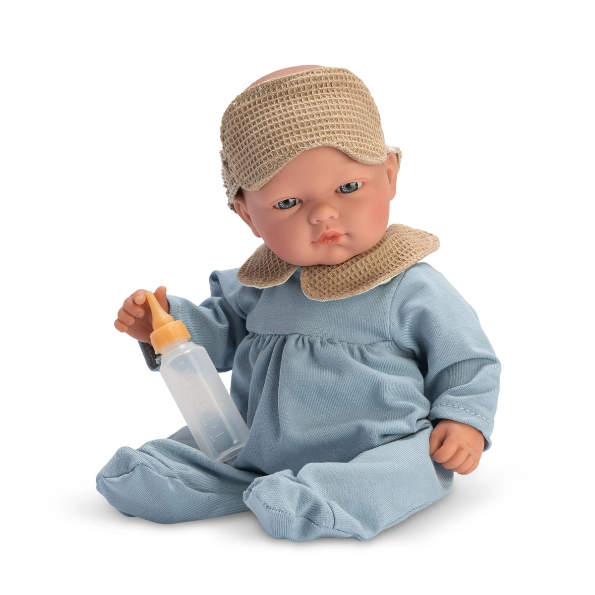 Bald doll in blue pajamas holding a bottle, wearing a tan sleep mask.