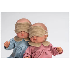 Two bald dolls in blue and pink outfits with beige blindfolds, seated closely together.