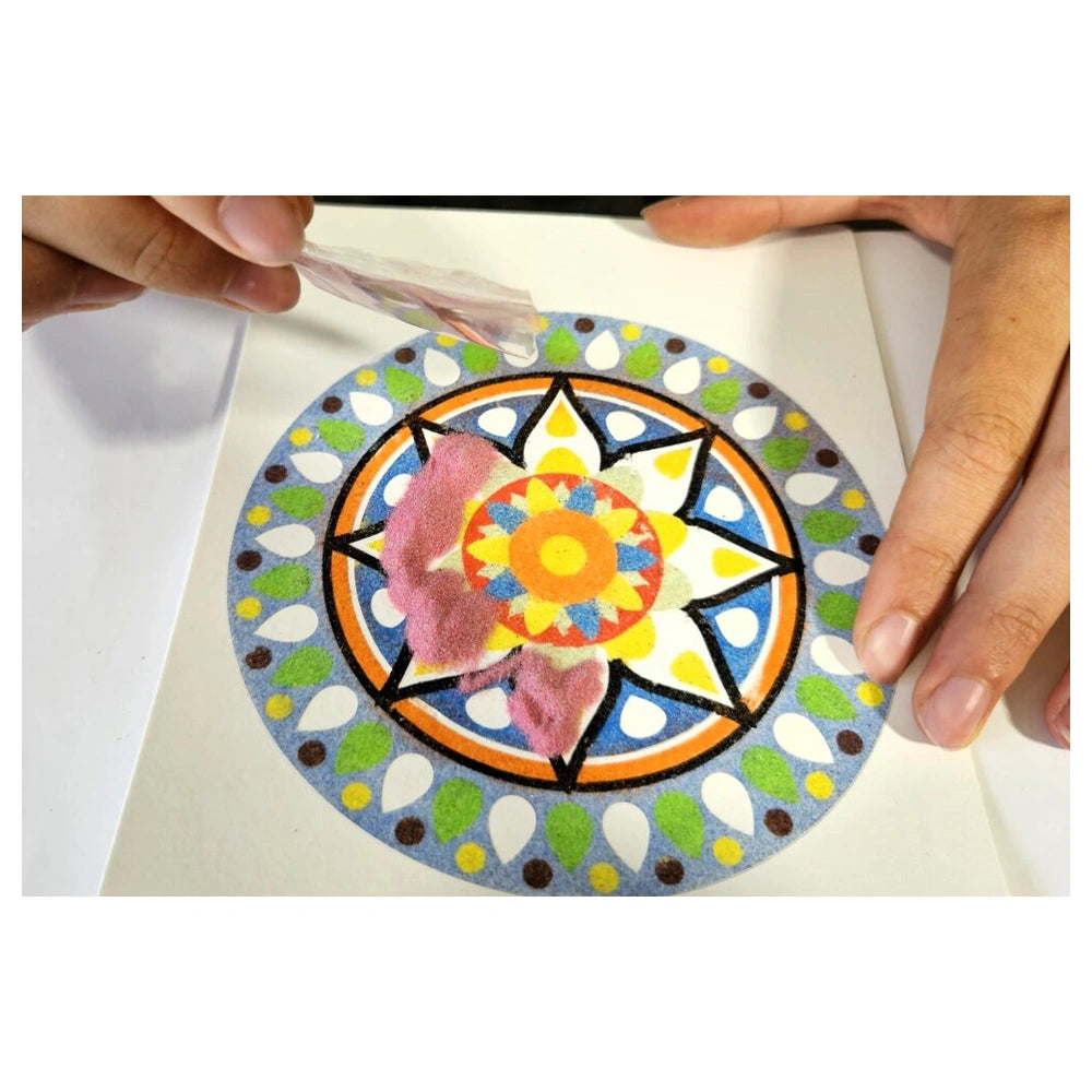 Alexander Sand Art Mandala craft project shows hands applying colorful fuzzy material to a circular patterned surface.