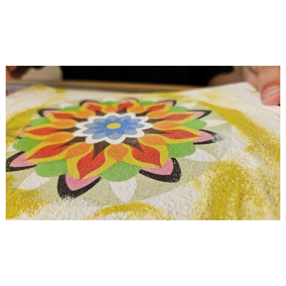 Colorful sand art mandala featuring a symmetrical flower design with vibrant petals in red, orange, yellow, and green.