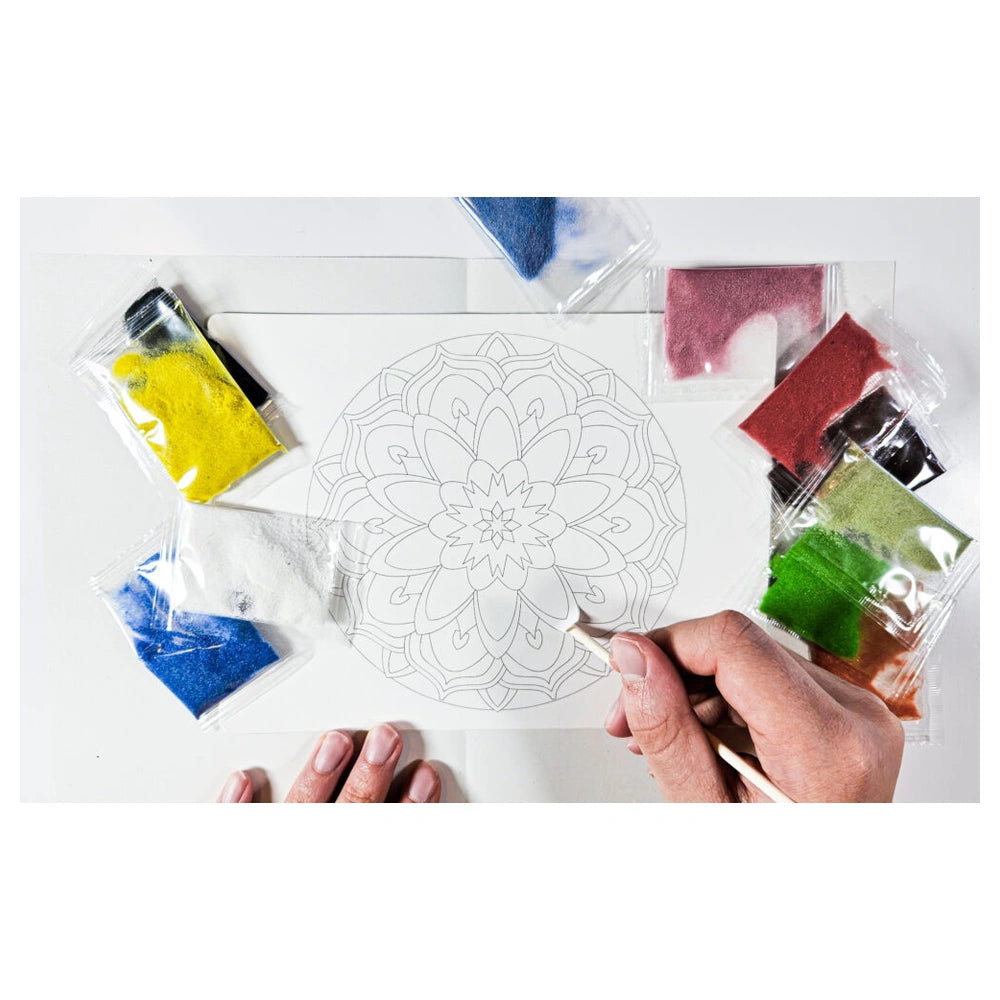Alexander Sand Art Mandala kit features hands applying colorful paint with a brush on cardstock for creative crafting.
