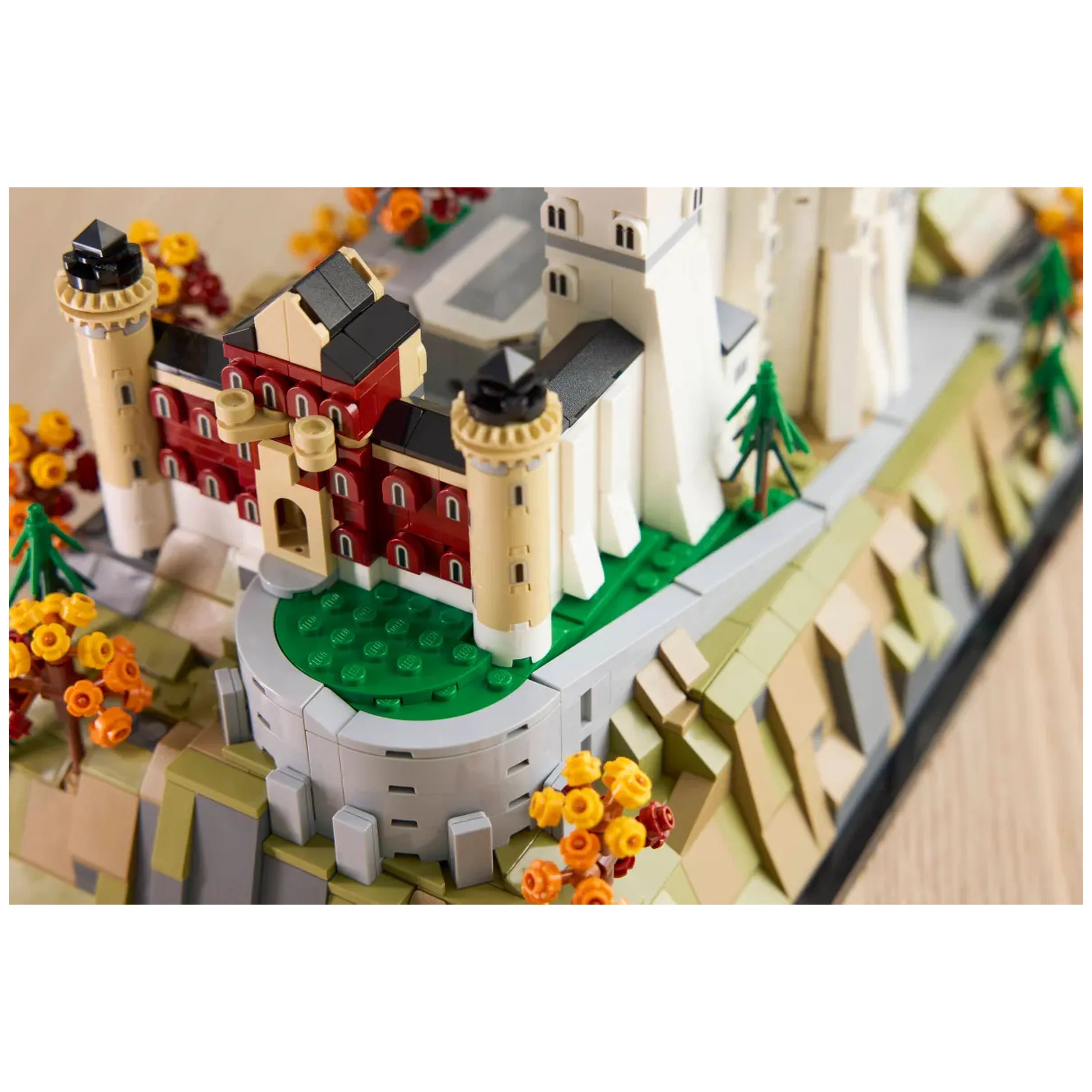 Detailed view of the LEGO Architecture Neuschwanstein Castle model, showcasing turrets, a red building with black roofing, and colorful autumn trees.