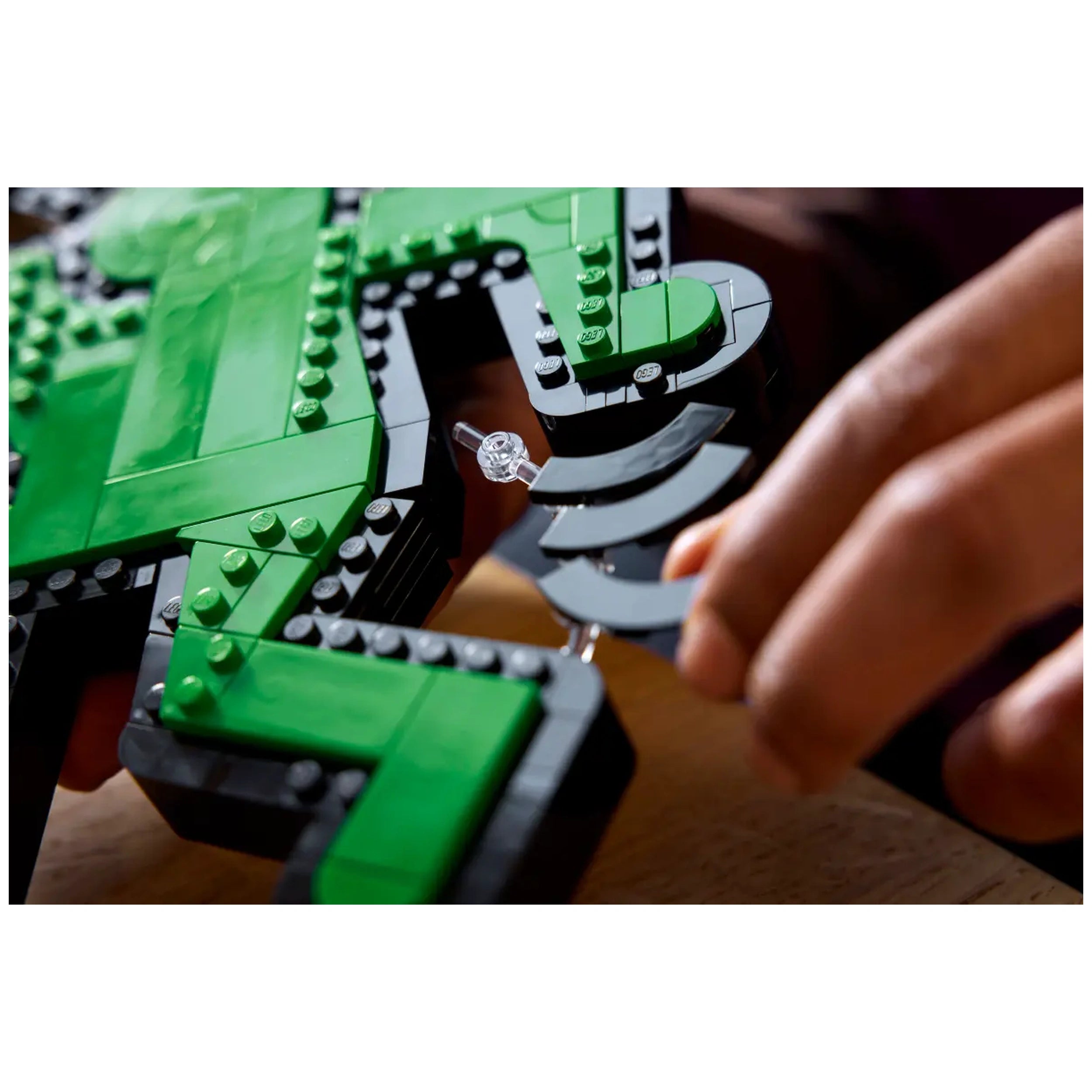 Close-up of hands assembling colorful LEGO bricks in a vibrant green and black design, creating a dynamic pop art figure.