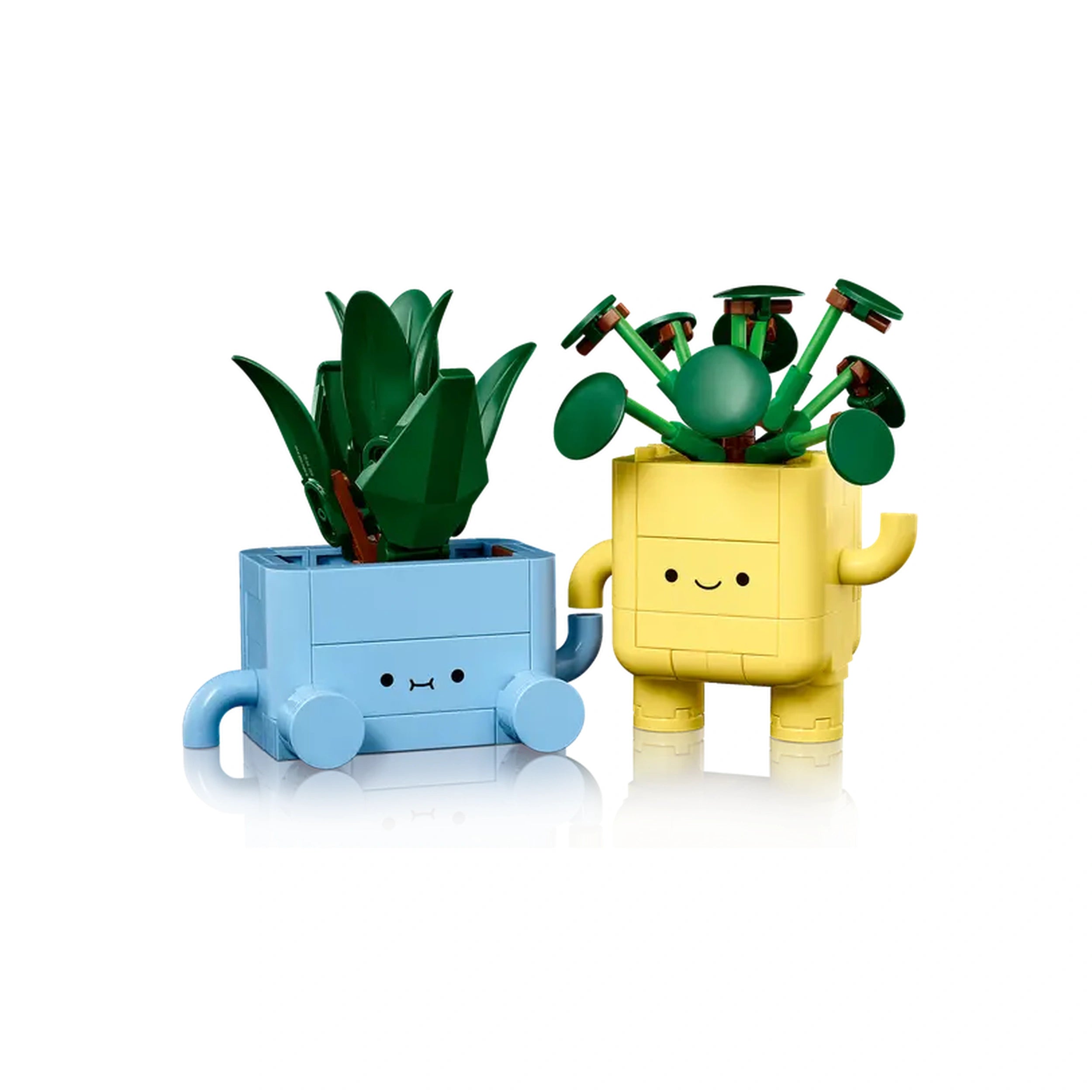 Two colorful LEGO plant toys: a tall green dracaena in a blue pot and a round green pilea in a cheerful yellow pot, both with smiling faces.