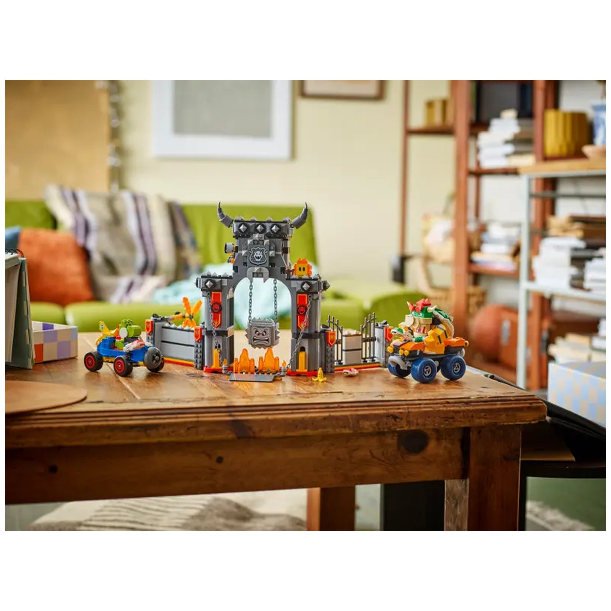 LEGO Bowser's Castle playset featuring a detailed castle gate, flames, and figures of Bowser and Yoshi riding karts on a wooden table.