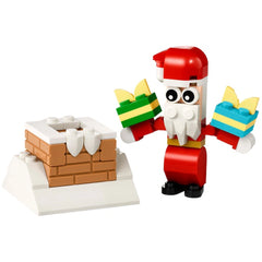 Cheerful Santa figure holding a wrapped gift in each hand, standing next to a snow-covered chimney made of LEGO bricks.