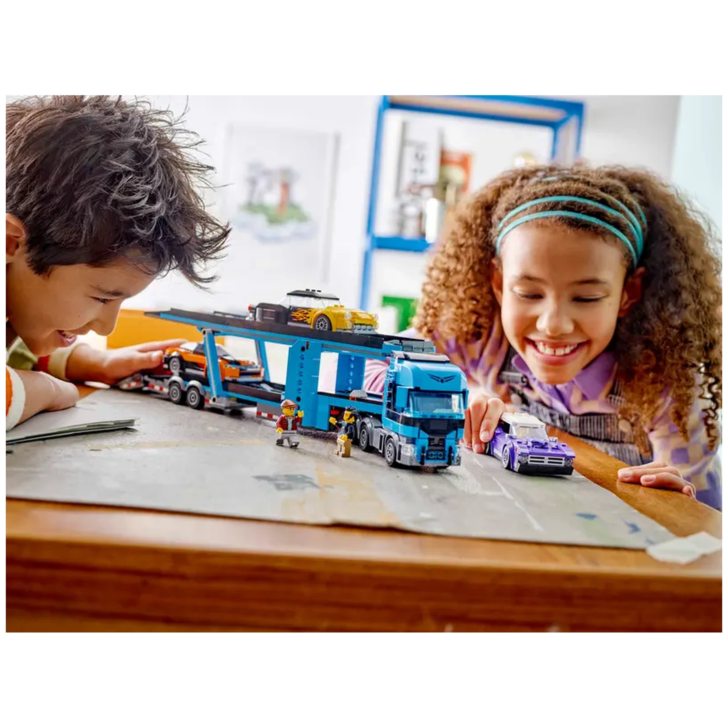 Two children engage with a vibrant LEGO® City Car Transporter set, featuring a blue truck loaded with colorful sports cars. The boy, smiling, leans in closely to inspect the vehicles, while the girl joyfully plays beside him. The backdrop includes bright shelves and artwork, enhancing the playful atmosphere of their imaginative play.