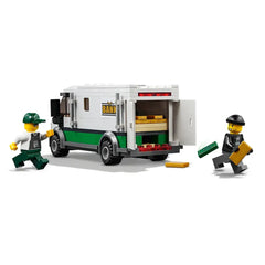 Two LEGO minifigures near a green and white bank truck; one has a baseball cap and uniform, while the other wears a black outfit and is holding a gold bar. The truck’s back doors are open, revealing stacks of gold bars inside.