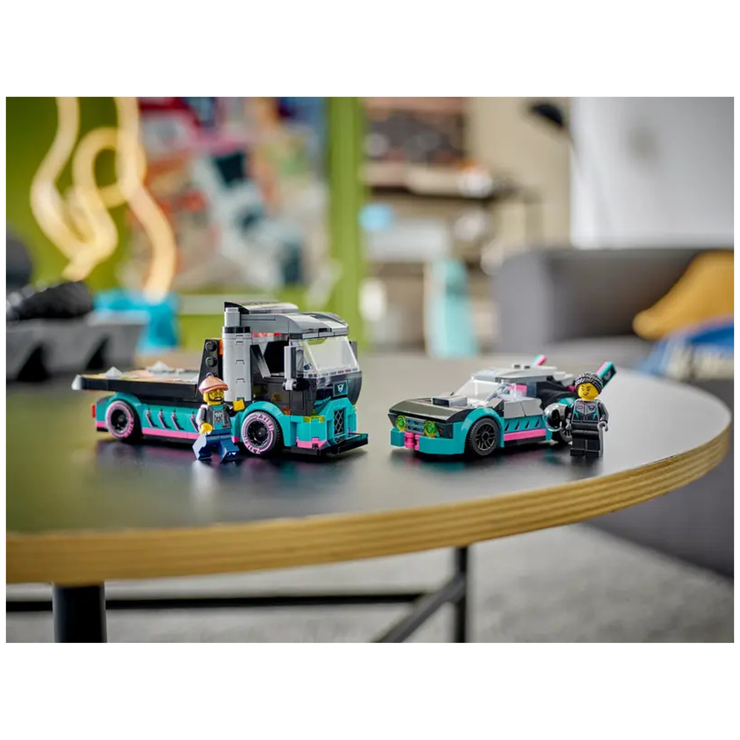 LEGO City Race Car and Car Carrier Truck set displayed on a round black table, featuring a bright blue truck and sleek race car, with two minifigures beside them.