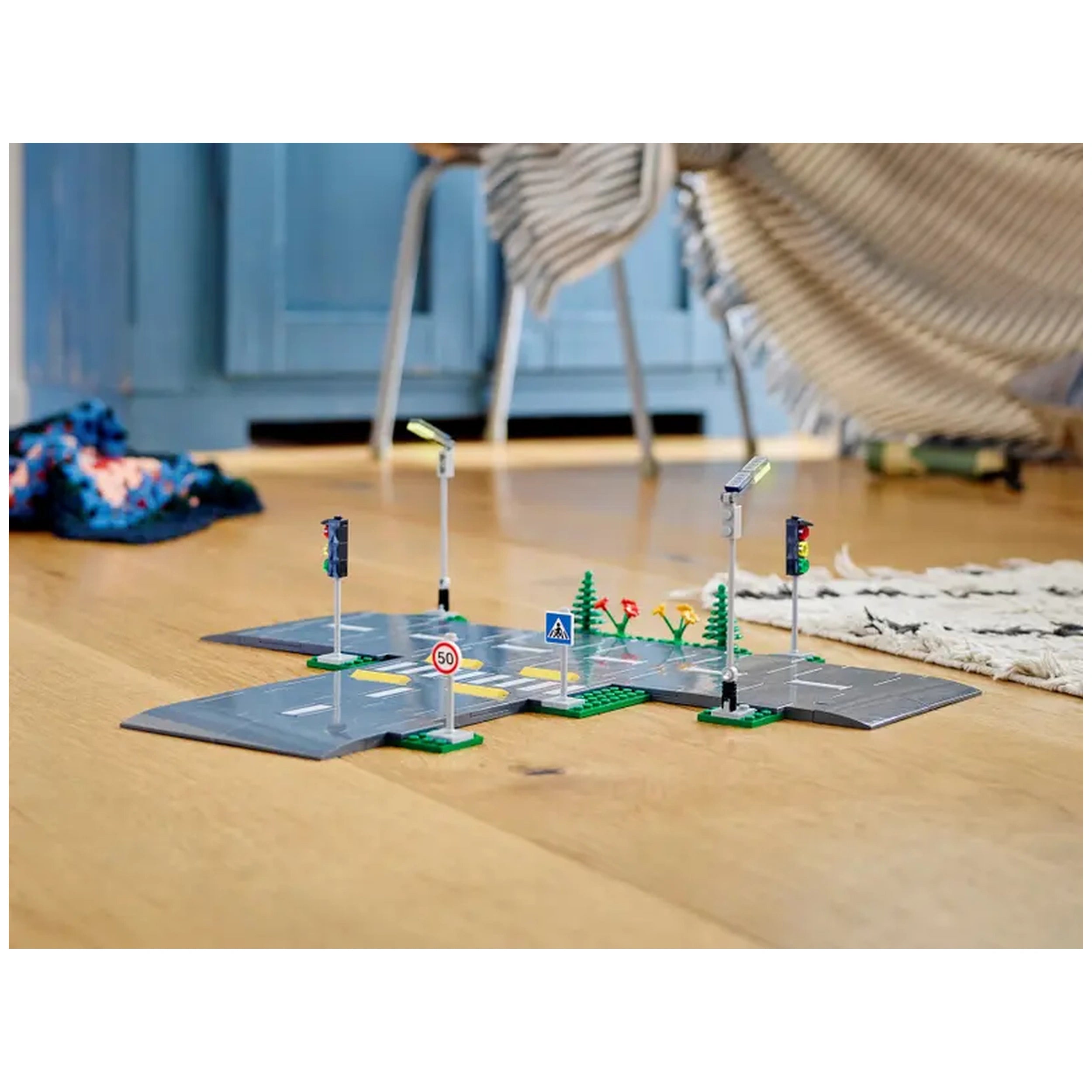 LEGO® City Road Plates construction set featuring five road plates, traffic lights, street signs, and miniature trees on a wooden floor.