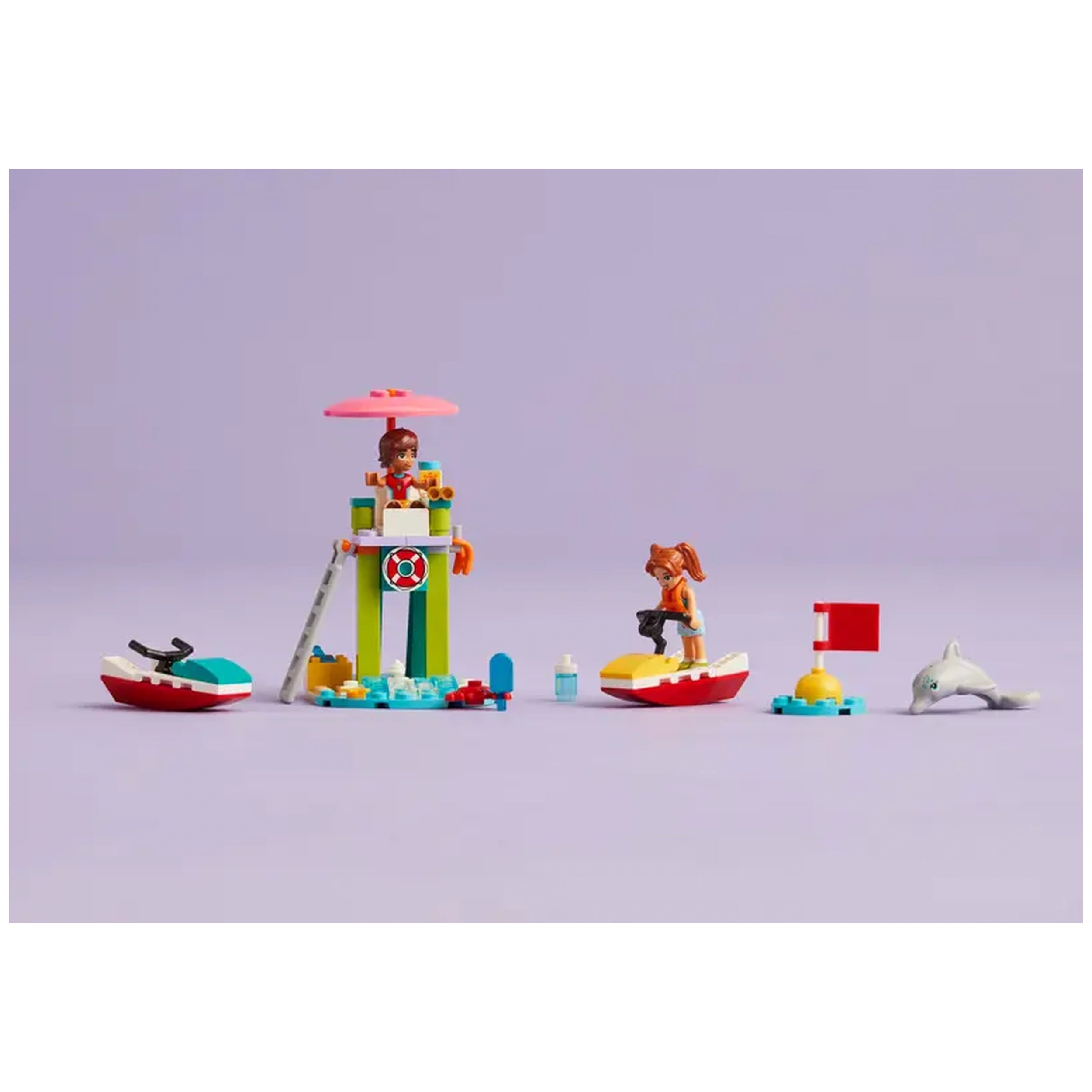 Two LEGO mini-dolls, Leo and Candi, at a colorful lifeguard tower with a pink umbrella. Water scooters and a playful dolphin figure enhance the beach scene, complete with accessories like sunscreen and a crab.