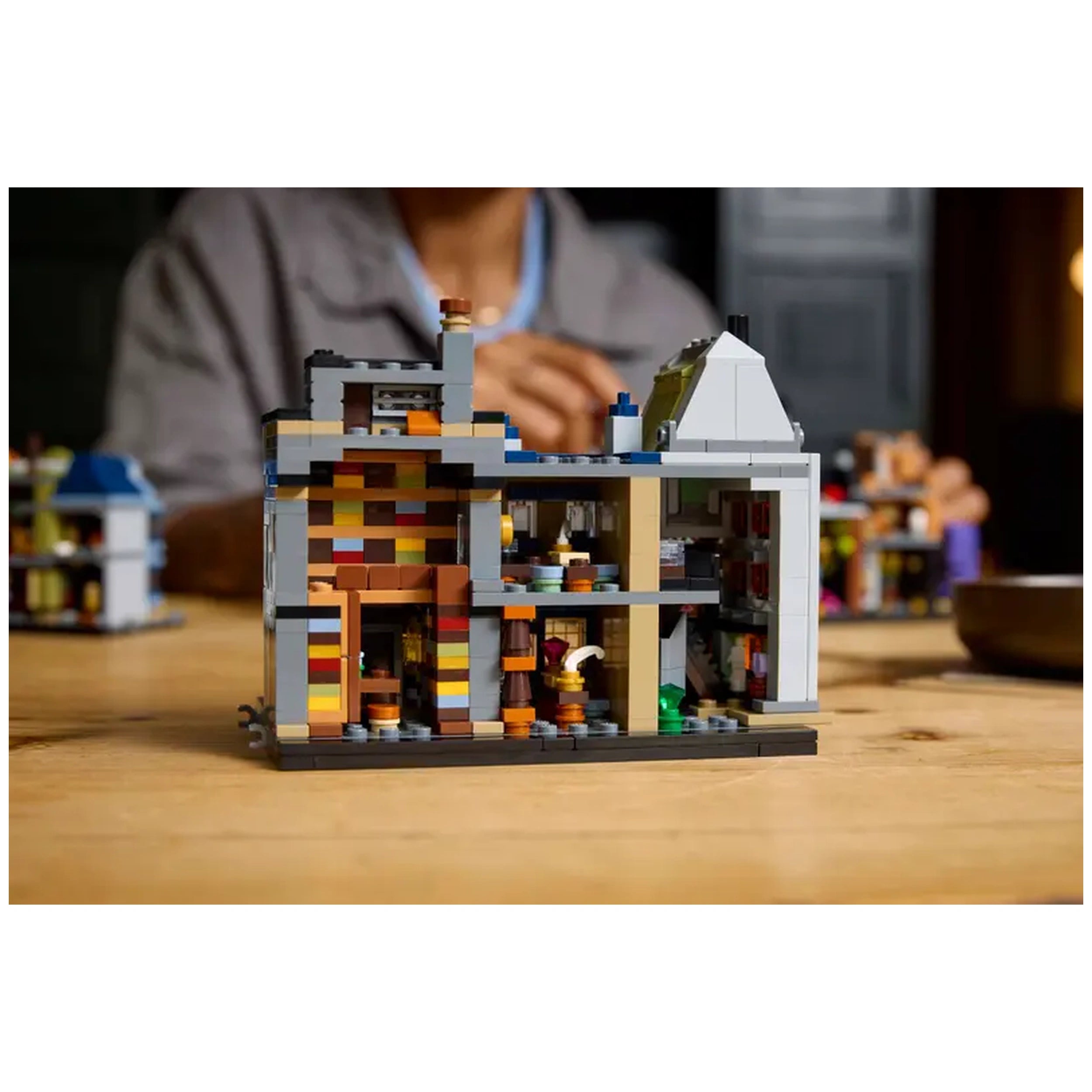 Microscale LEGO® Harry Potter™ Diagon Alley™ model showcasing colorful shops and intricate details, set on a wooden table.