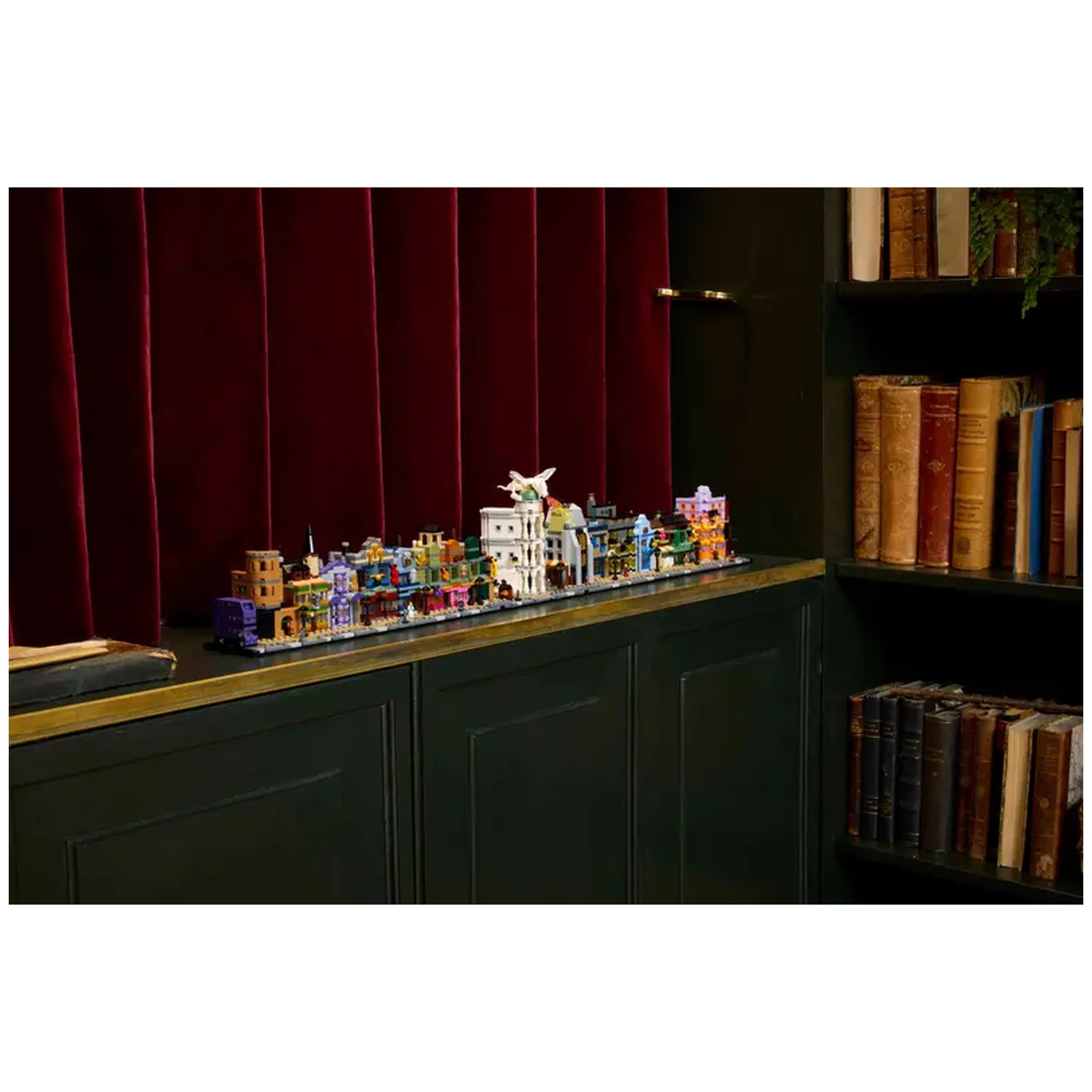 Colorful LEGO® Harry Potter™ Diagon Alley™ microscale buildings displayed on a dark wooden shelf, against a rich burgundy backdrop.