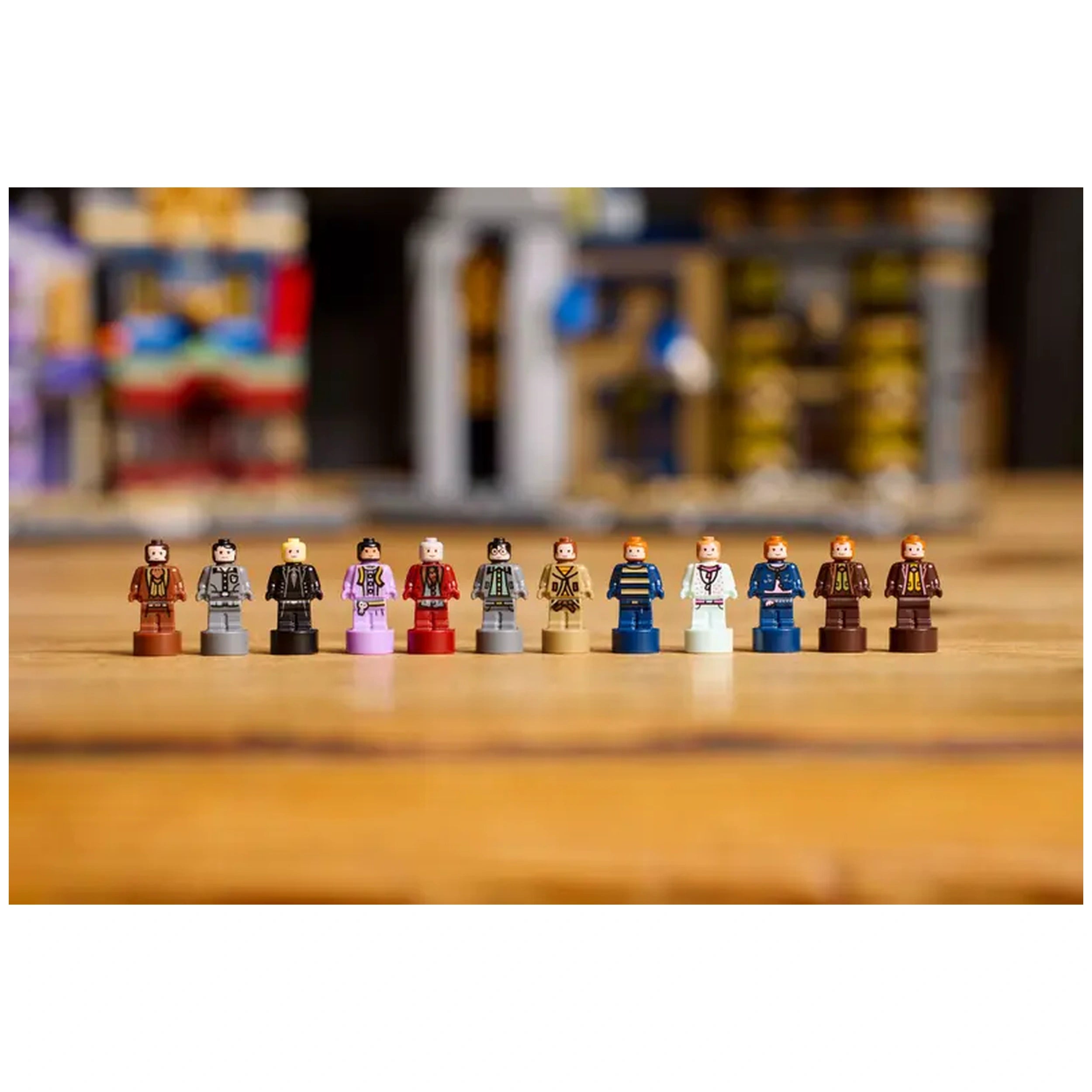 A collection of LEGO® Harry Potter™ microfigures arranged in a line, showcasing various characters with distinct outfits and hair colors, set against a blurred background of a whimsical Diagon Alley scene.